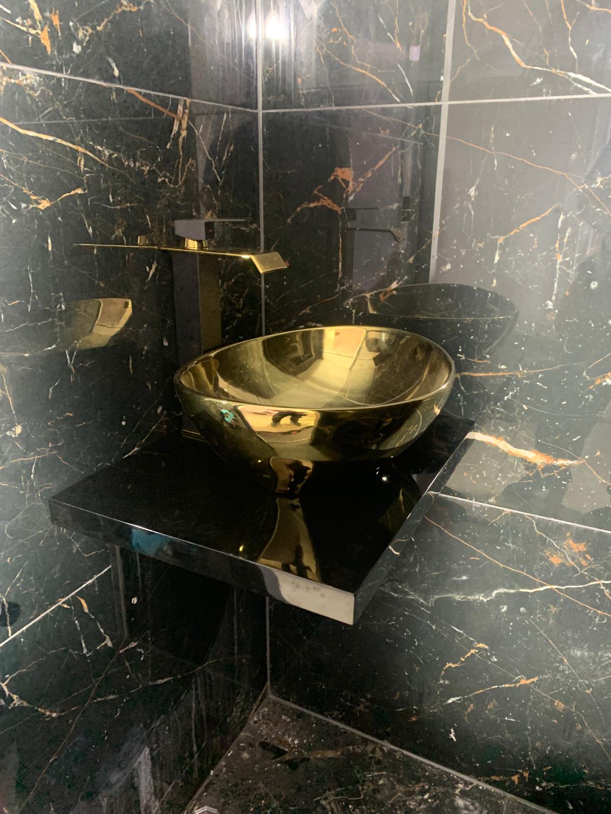 Luxe wastafel met gouden kraan op zwart marmer