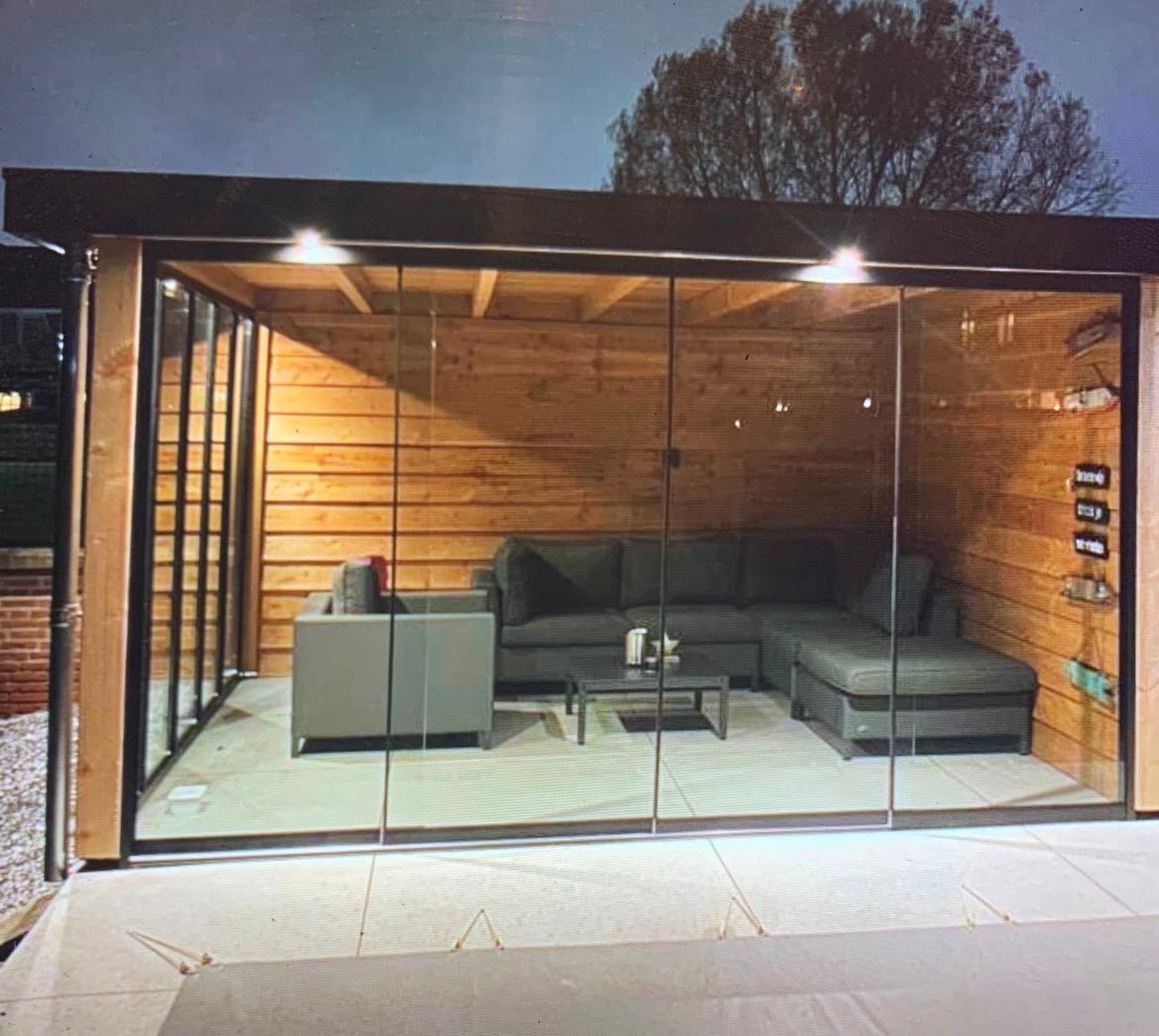 Tuinhuis met glazen wanden verlicht in de avond